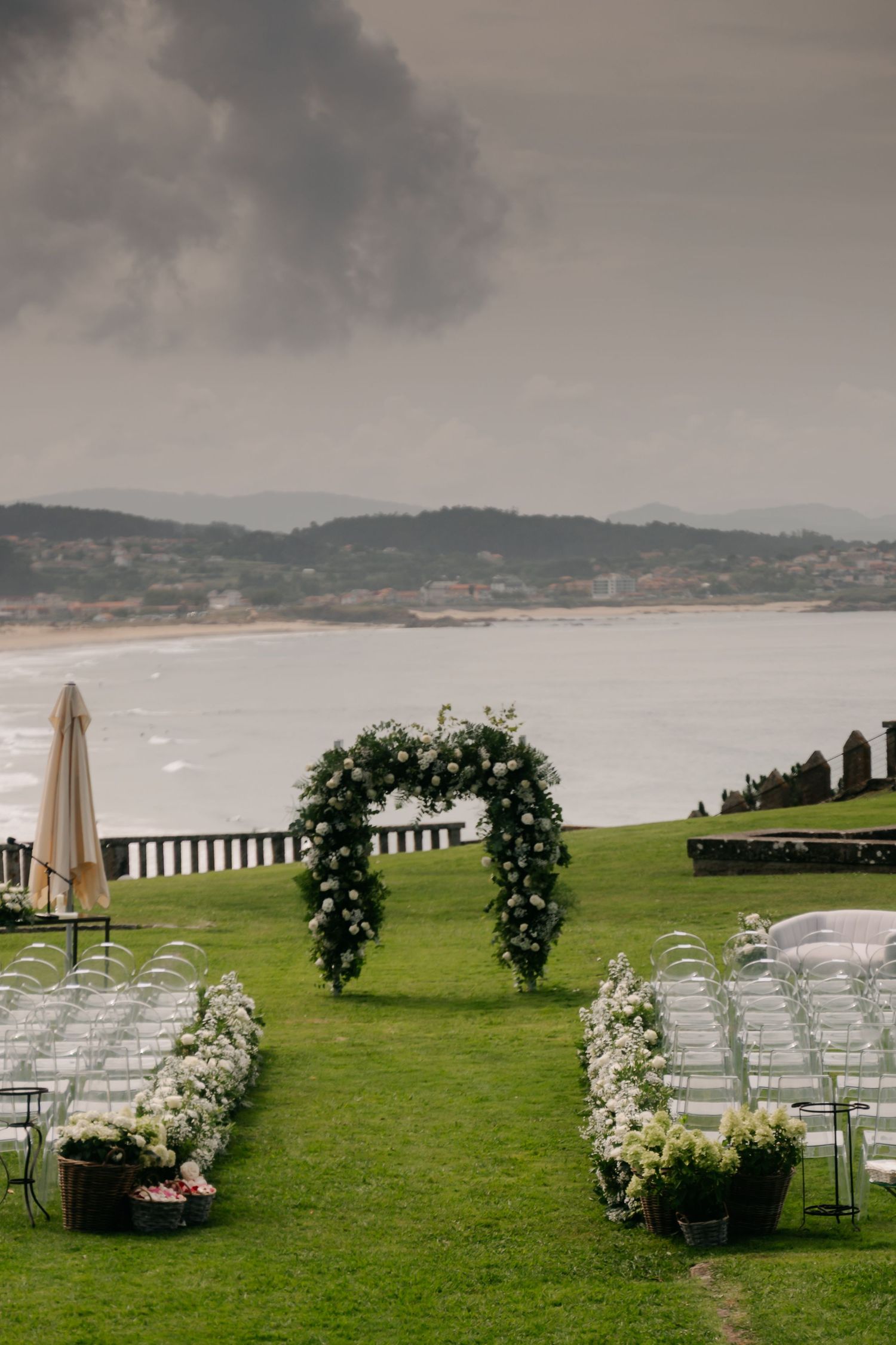 Rows of white chairs set up for an outdoor wedding ceremony on a grassy lawn overlooking a misty coastal bay.
