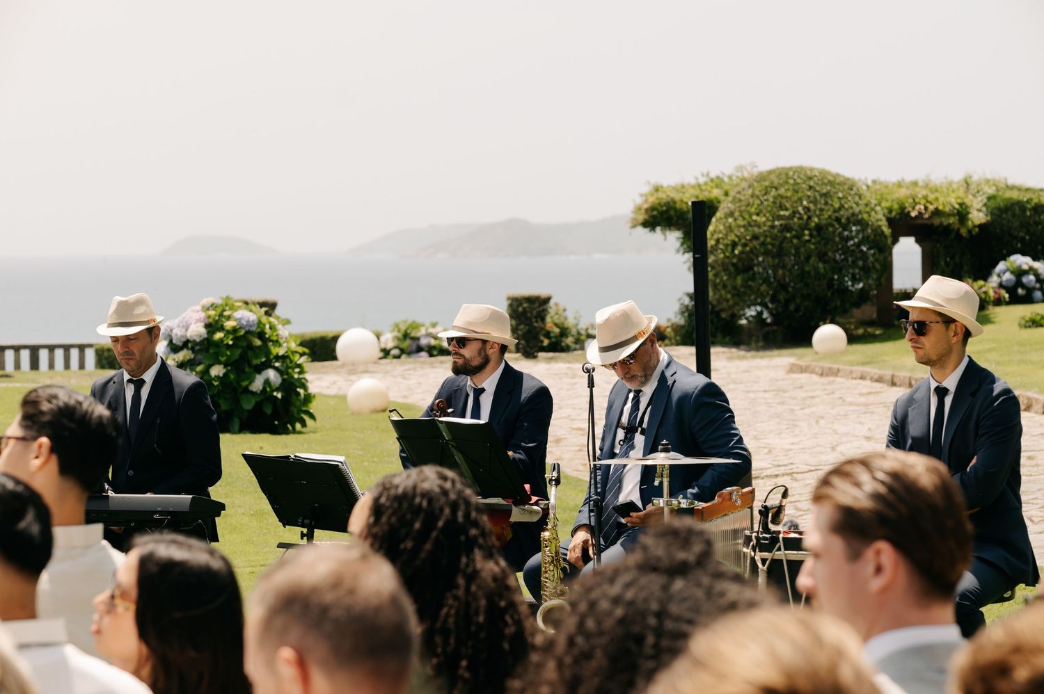 A panoramic view of guests seated outdoors at a wedding ceremony with mountains and greenery in the background.