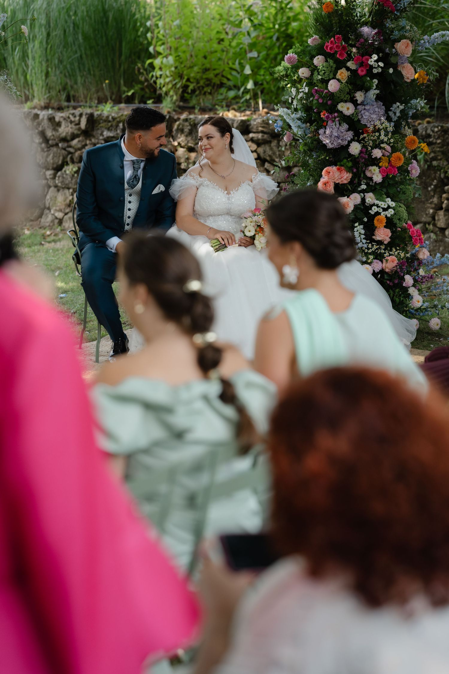 A romantic garden wedding ceremony with colorful floral arrangements and guests in soft pastel dresses.