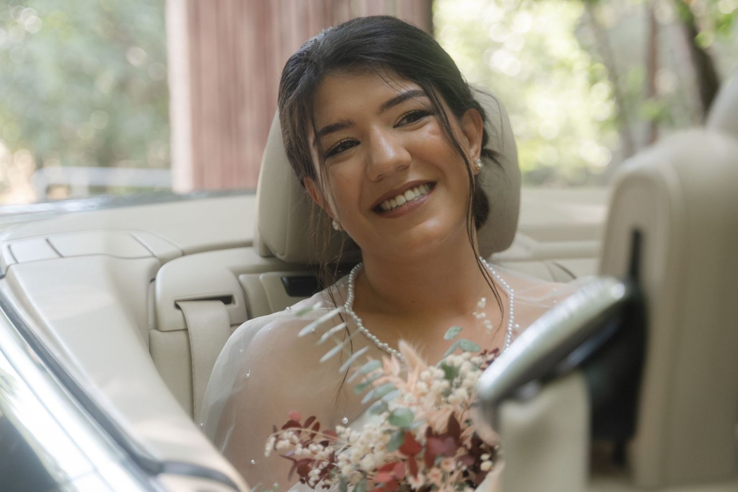 A bride in a white wedding dress with lace details poses during a wedding photoshoot.