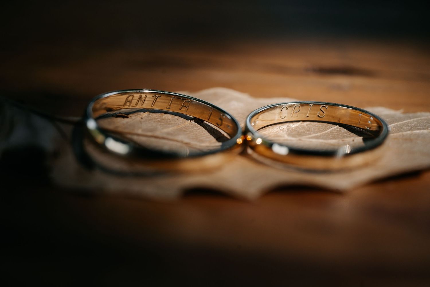 Wedding rings photographed in dramatic lighting with shallow depth of field on a dark surface.