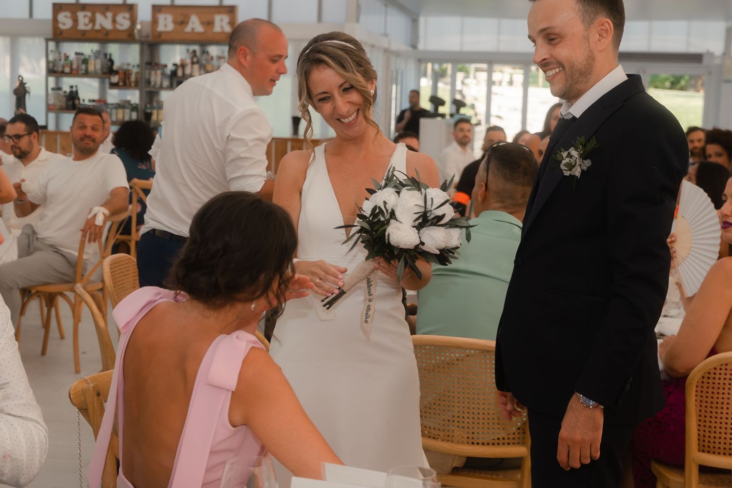 Wedding reception guests mingle and socialize in an elegant indoor venue with white decor.