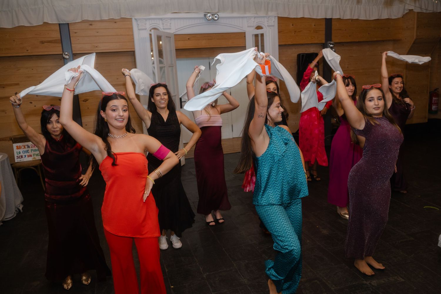 Wedding guests waving napkins while dancing in a reception hall.