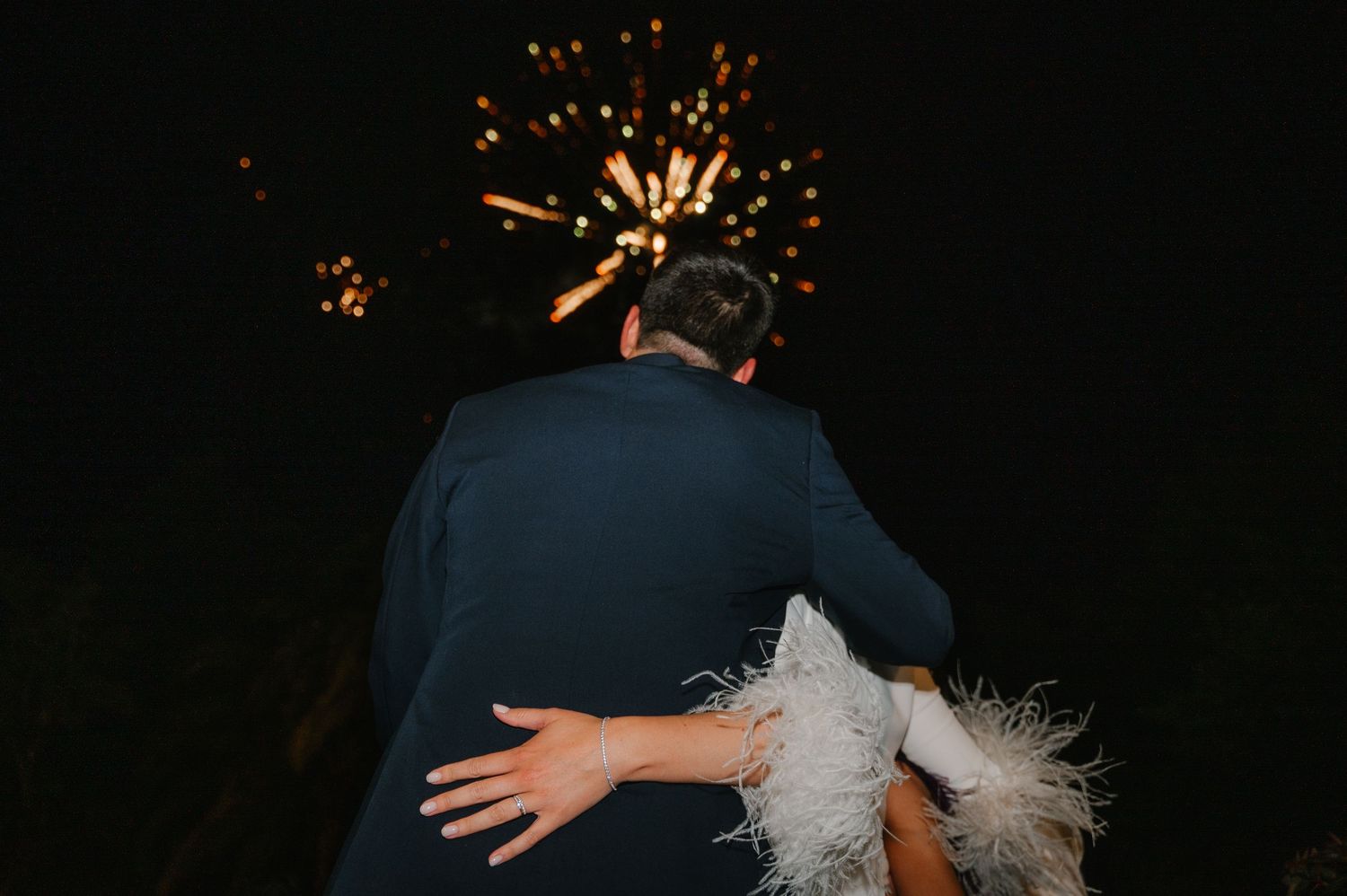 A couple dances under sparklers at night during a wedding celebration.