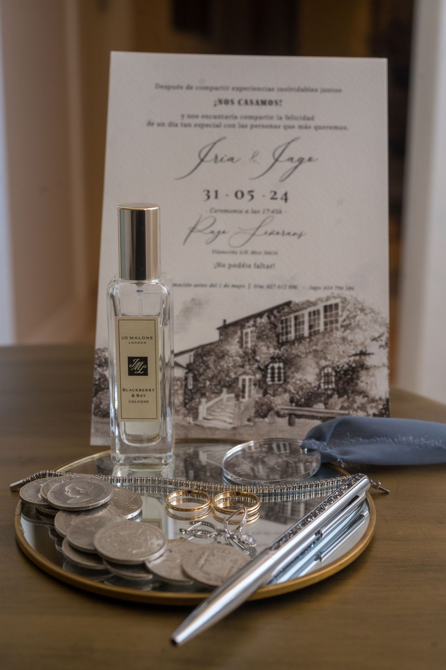 Elegant perfume bottles and wedding stationery arranged on wooden surface with vintage architectural sketches.