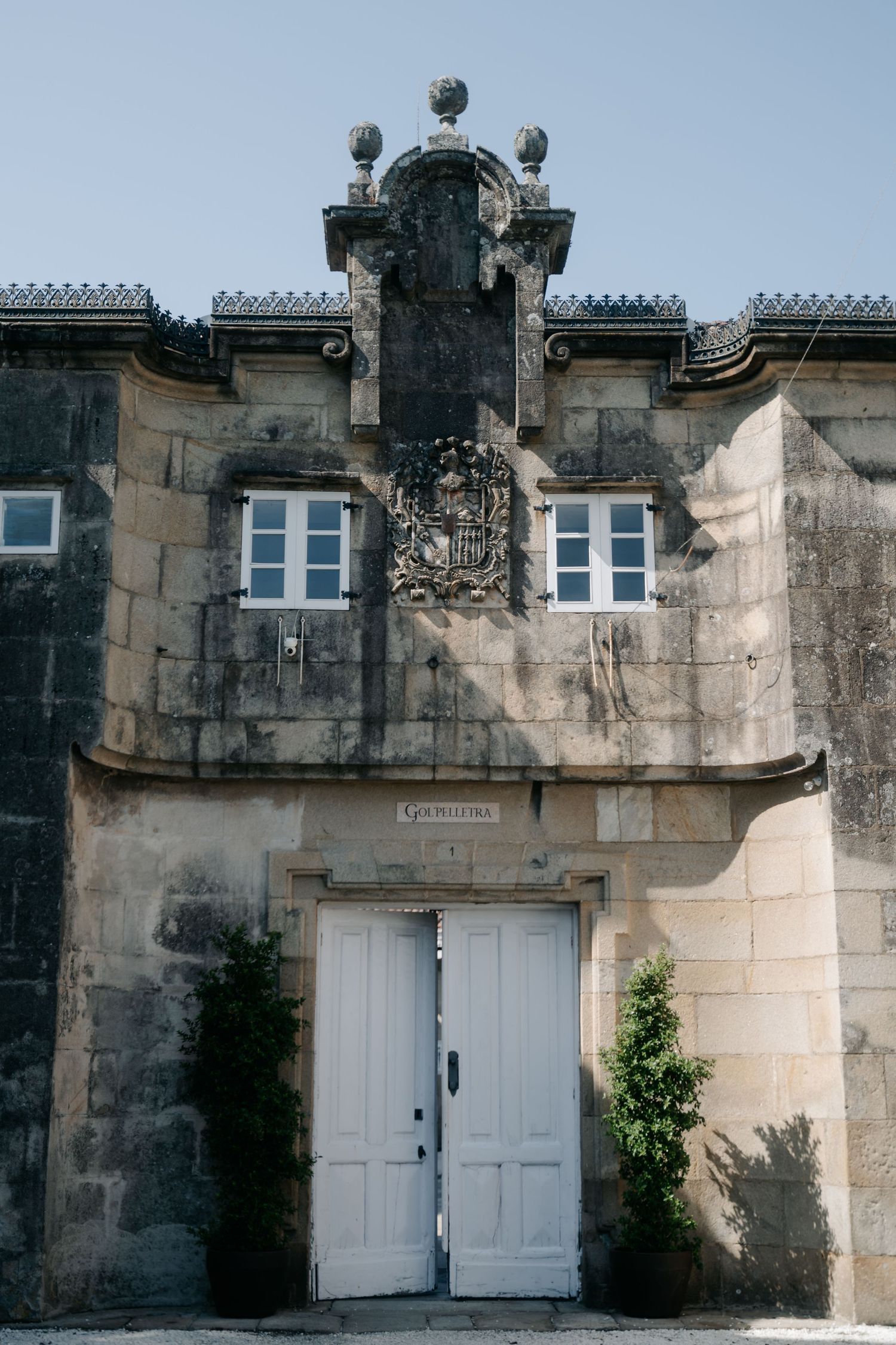 Historic stone building entrance with ornate architectural details and white double doors in a classical European style.