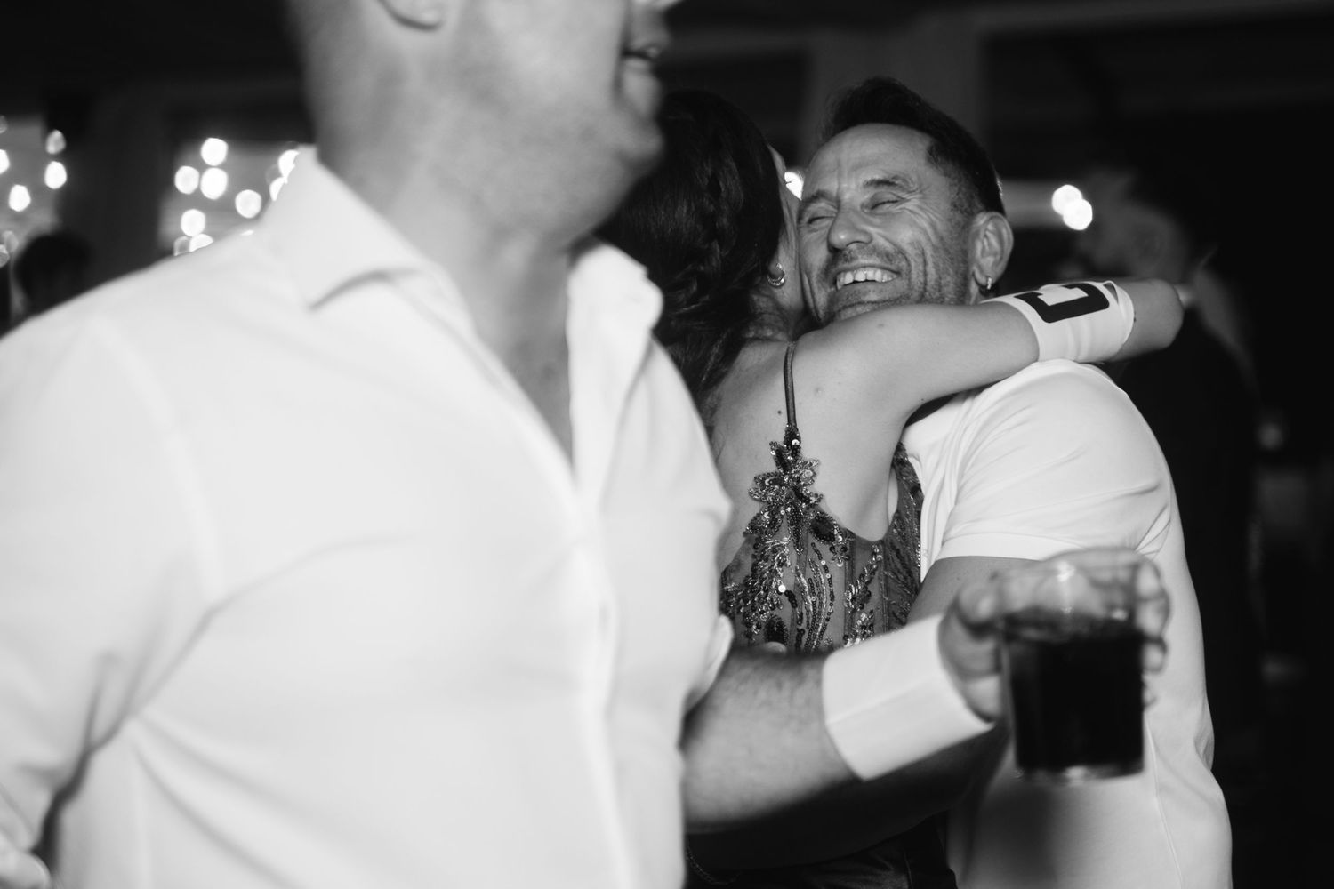 Black and white candid photos of guests dancing and celebrating at a lively wedding reception.
