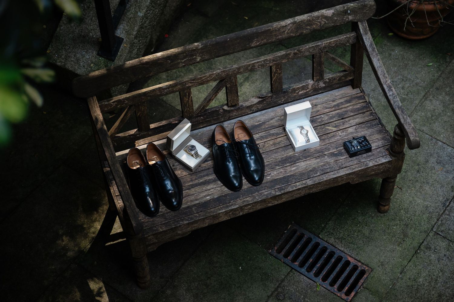 A dark wooden bench with shoes arranged neatly along its edge sits against a shadowy wall.