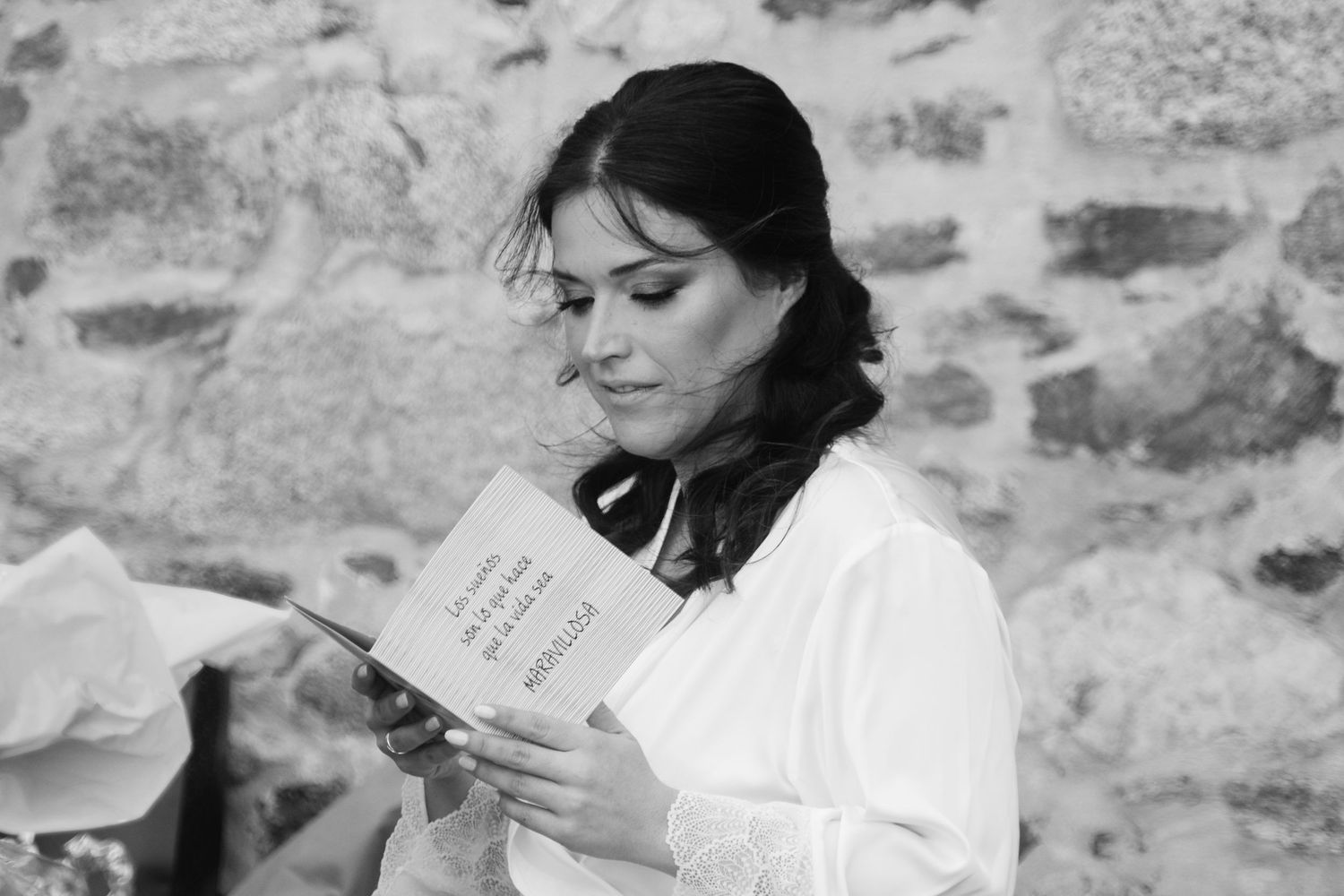 Five black and white photos show someone reading a book against a stone wall background.