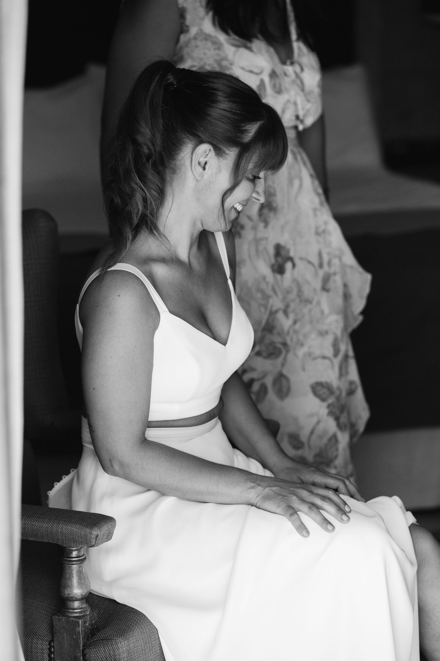 Women in white dresses preparing for wedding ceremony in black and white photography.