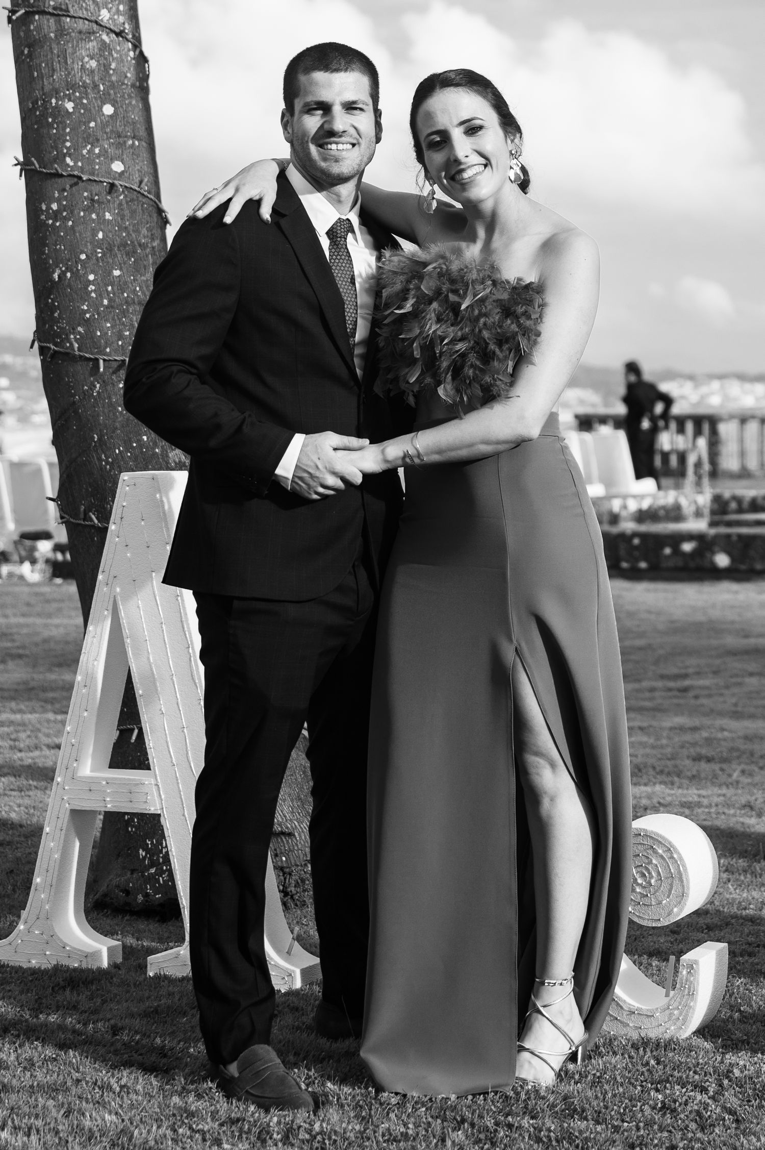 A black and white photo series showing a couple posing outdoors with large decorative letters on grass.
