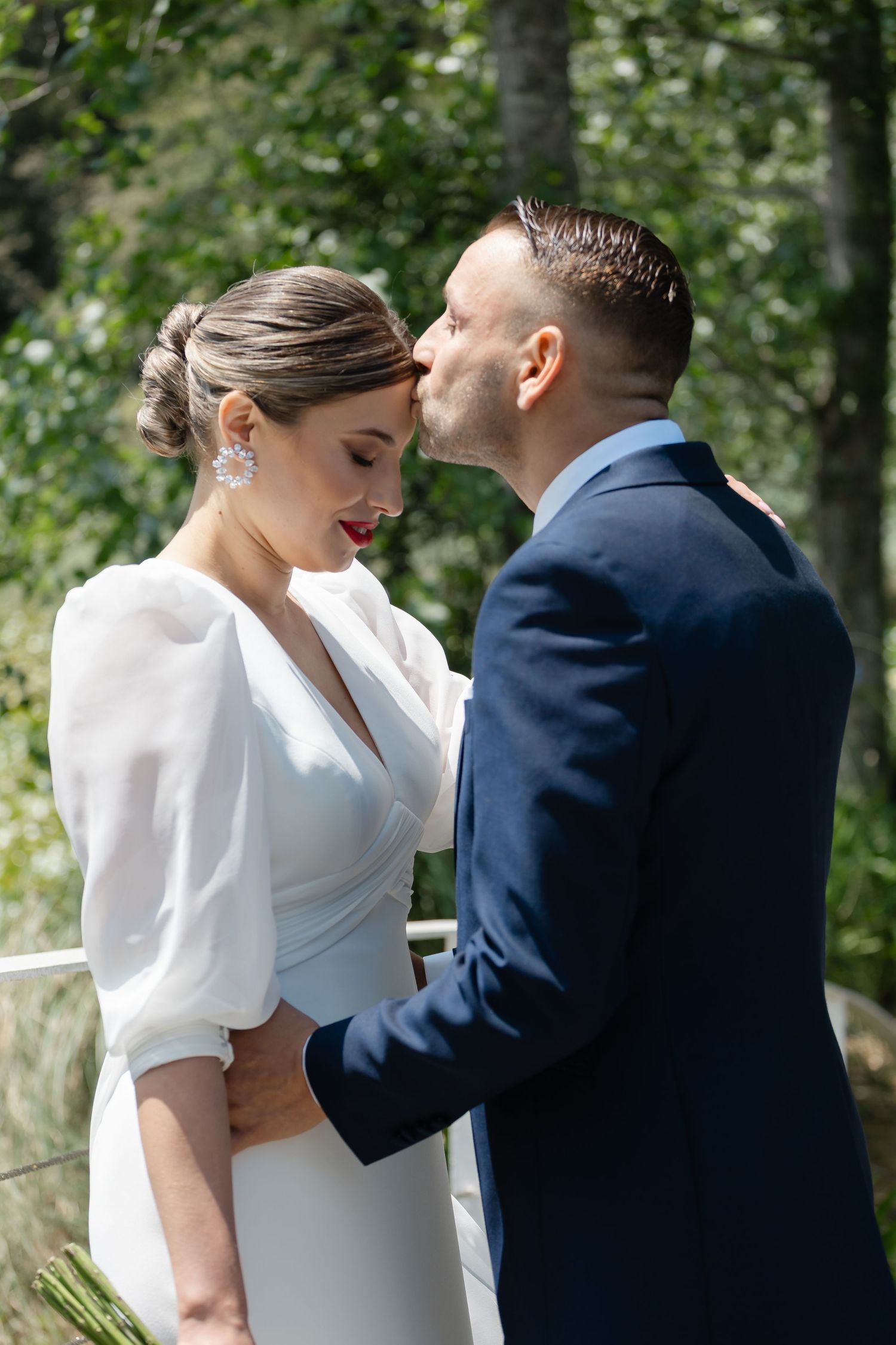 A romantic wedding moment captured in an outdoor garden setting with elegant attire and natural greenery.