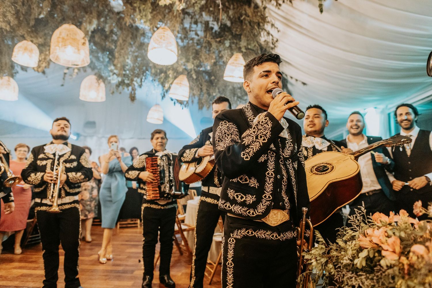 Wedding band performing on stage with instruments under blue-tinted lighting and decor.