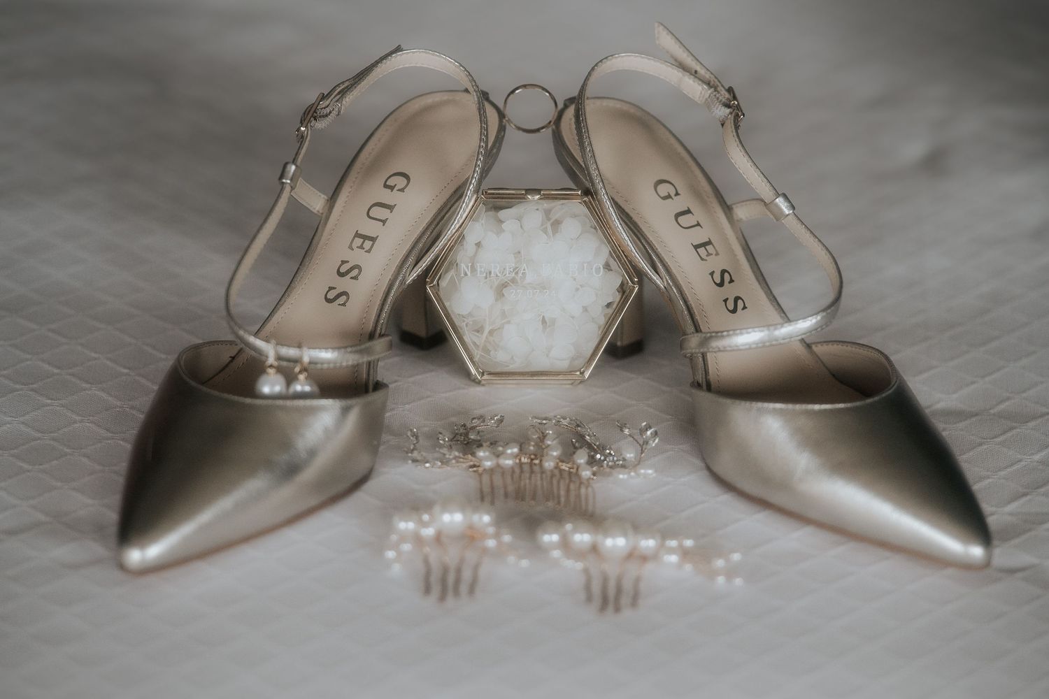 Elegant silver metallic high heel shoes arranged with delicate jewelry and accessories on a gray surface.