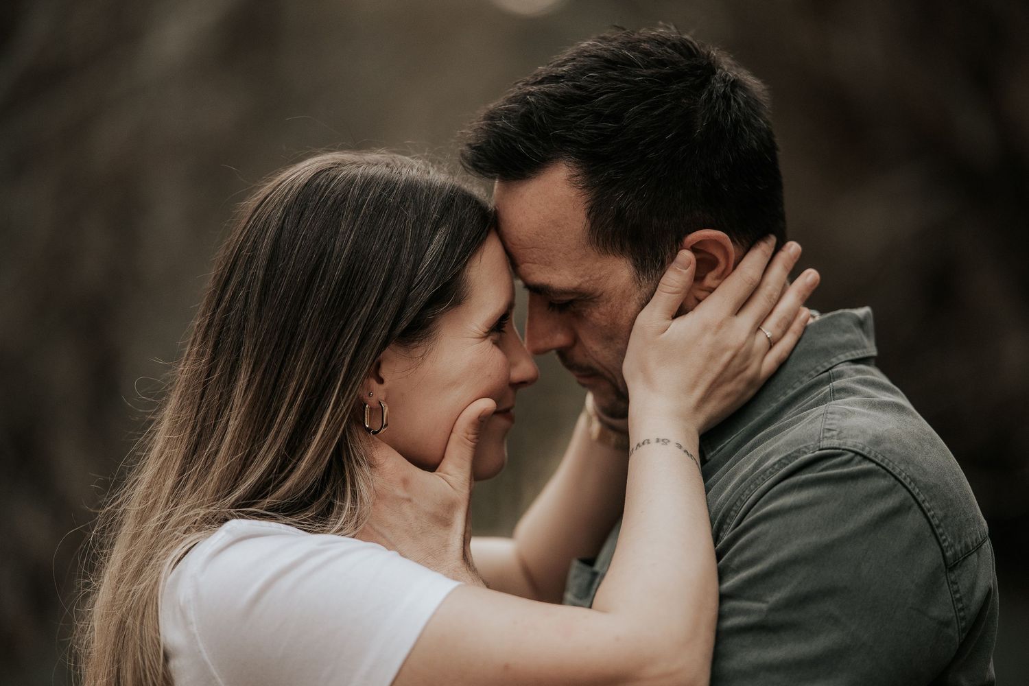 Intimate couple sharing a tender romantic moment against a moody dark background.