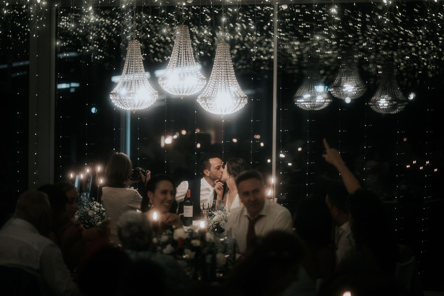 String lights illuminate a dimly lit indoor venue creating a warm and romantic atmosphere for an evening event.