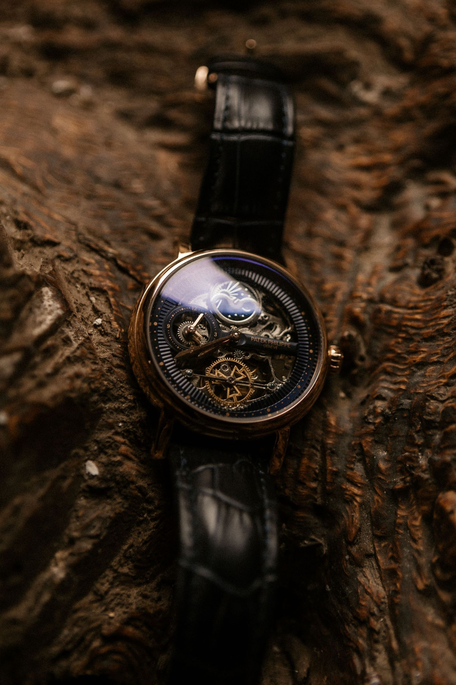 Luxury mechanical watch with exposed skeleton movement and black leather strap resting on textured wooden surface.