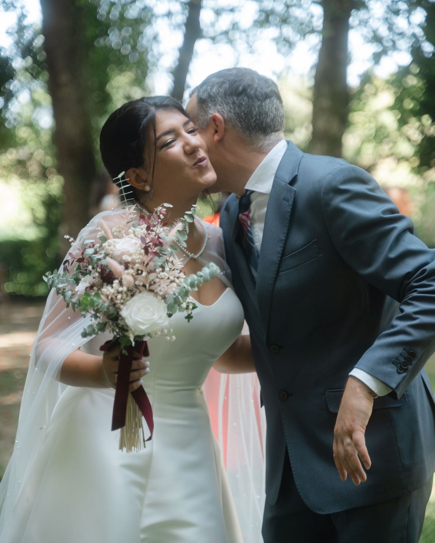 A tender moment captured during an outdoor wedding ceremony with delicate white floral bouquet details.