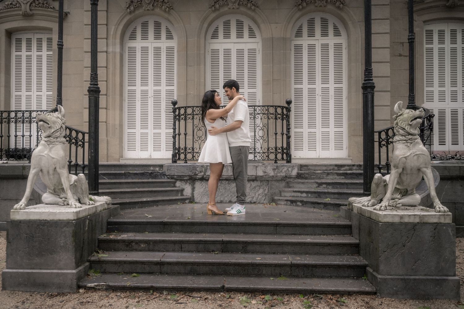 Couple embraces on grand stone steps of historic building during romantic photoshoot.