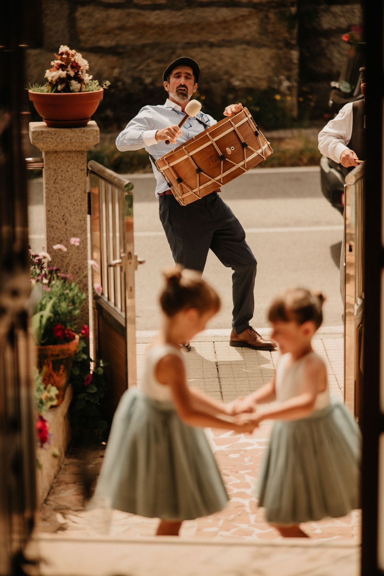 Young dancers in sage green dresses perform at an outdoor venue with stone walls and decorative pillars.