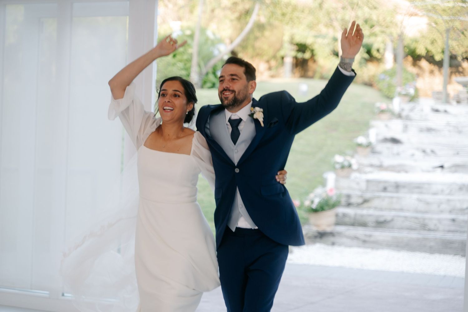 A couple dances joyfully in a light-filled venue during their wedding celebration.