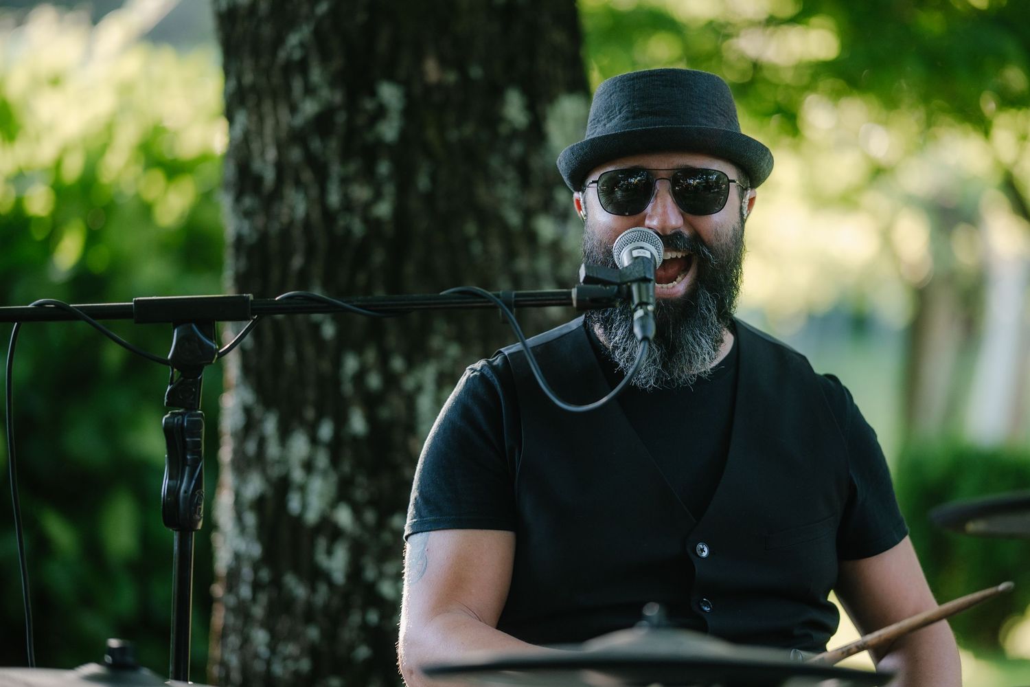 A musician in black attire performs at an outdoor event.