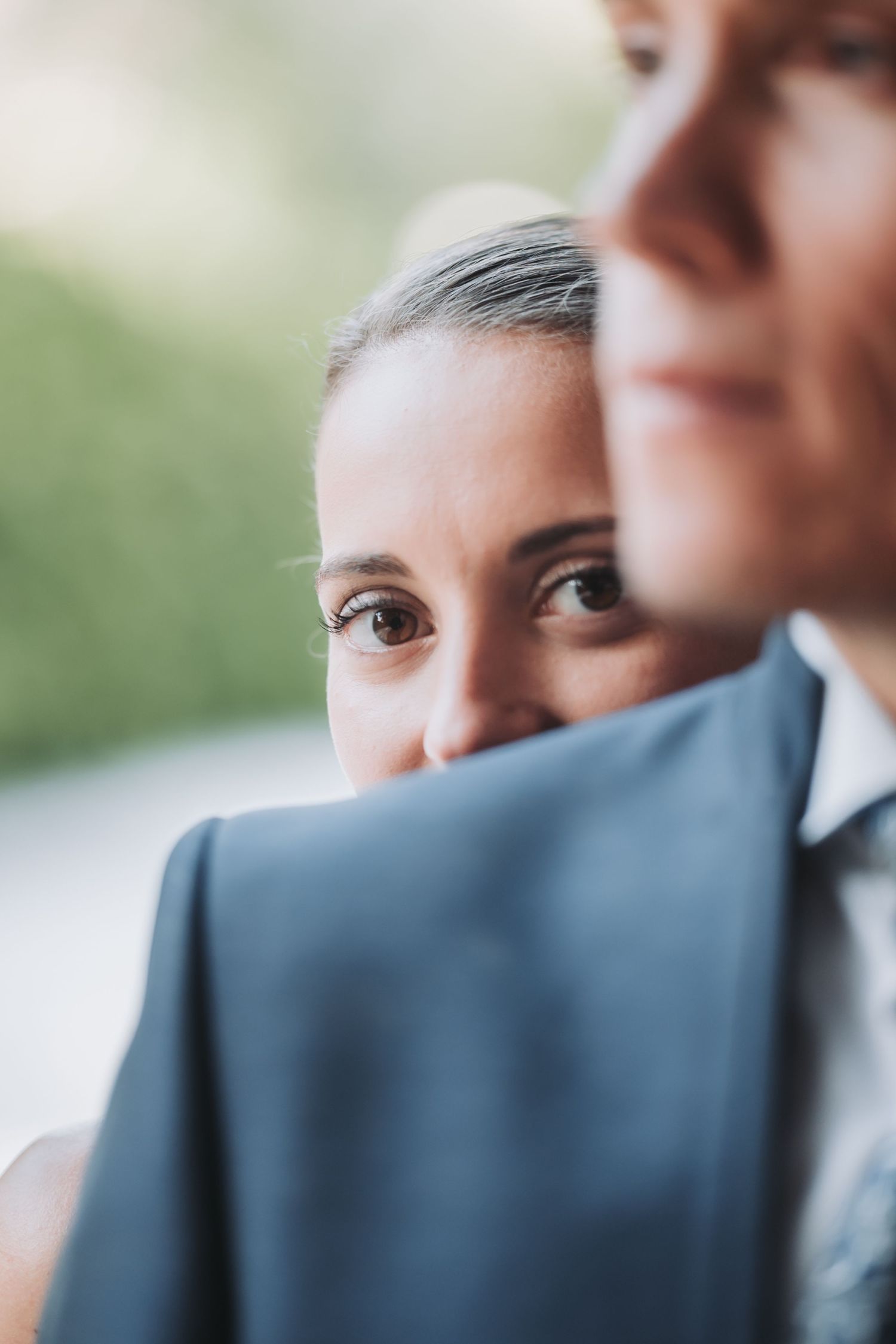 Close-up intimate portrait of newlyweds sharing tender moment against soft natural background.