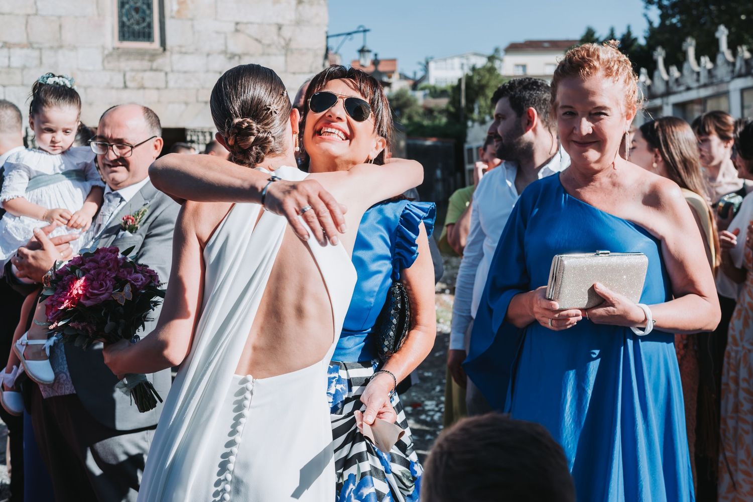 Wedding guests celebrate and dance together during an outdoor reception in bright summer weather.
