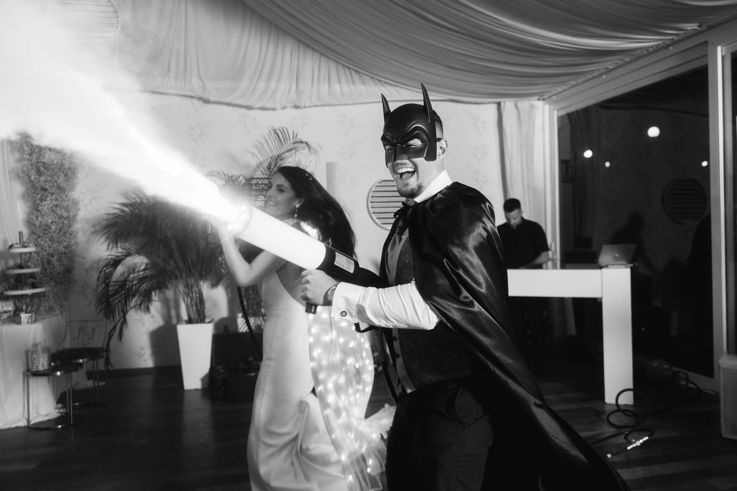 A costumed entertainer sprays fog effects while performing at an indoor event.