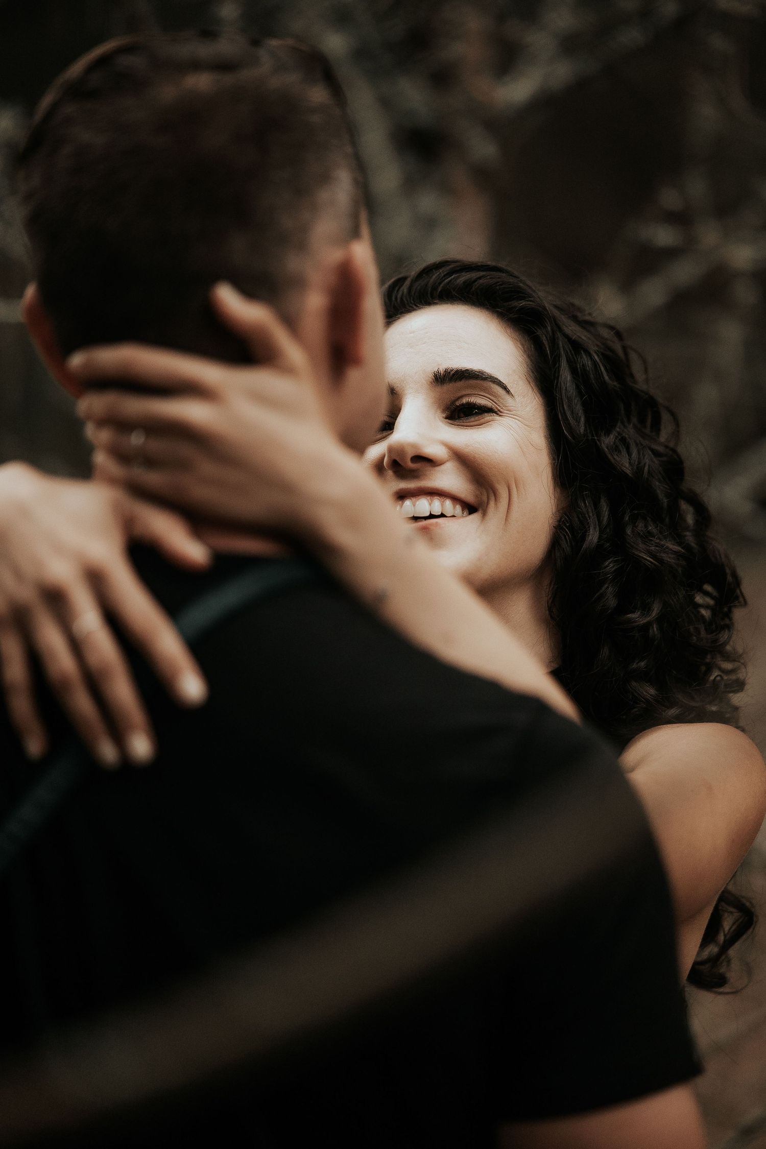 A couple embraces intimately, with the woman smiling joyfully as she looks at her partner's face.