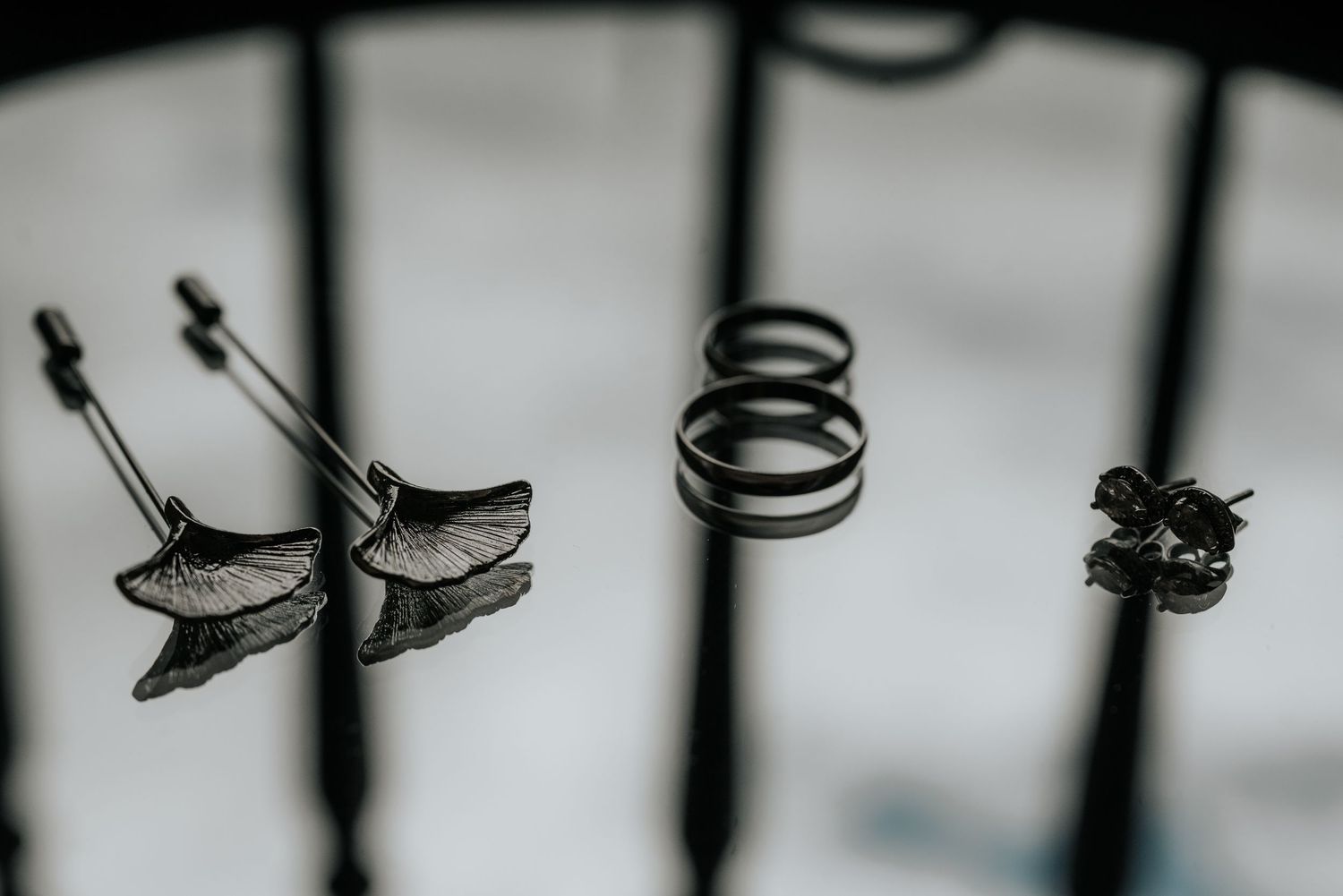 Black and white macro photograph of metal wedding rings casting shadows on a textured surface.