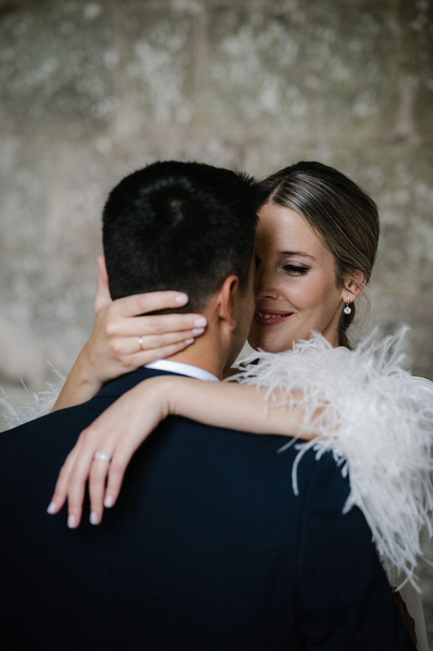 Intimate wedding portrait showing delicate feather details on white dress sleeve.