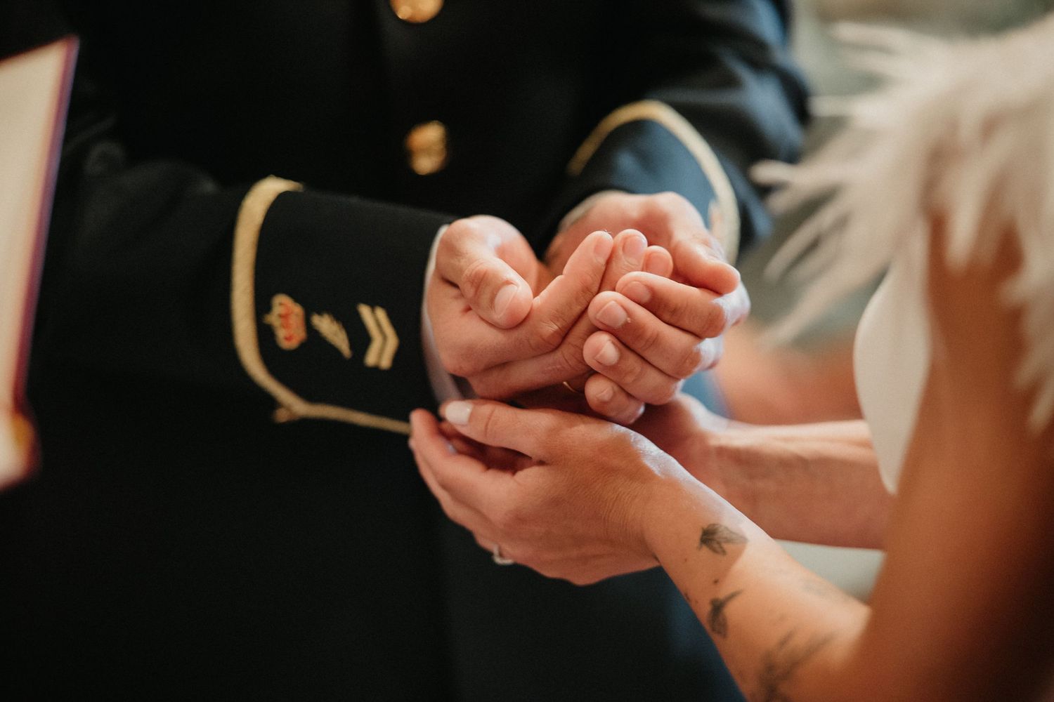 Close-up shot of hands during a wedding ceremony with warm lighting in the background.