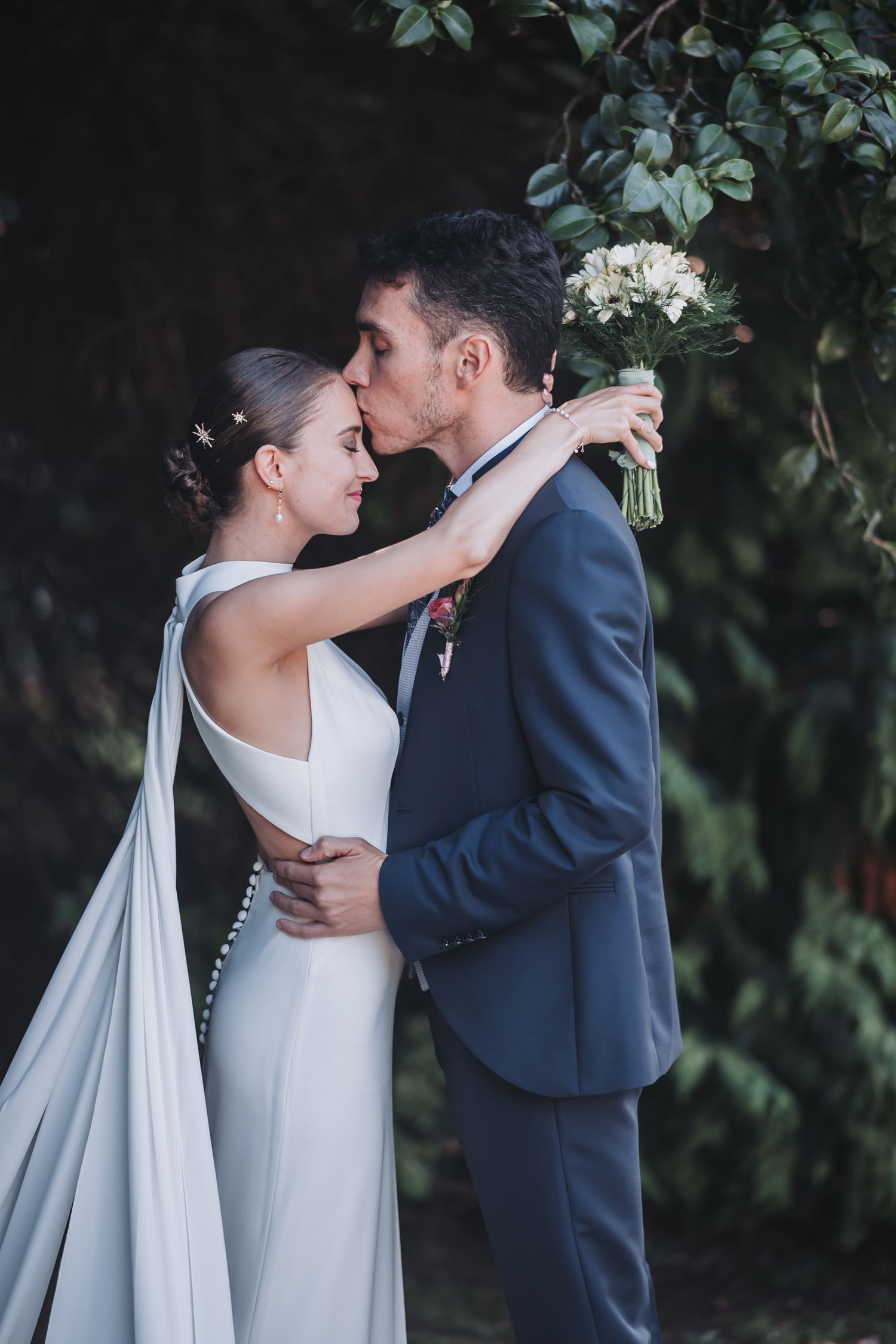 Romantic wedding couple embraces in an intimate moment against a lush garden backdrop.