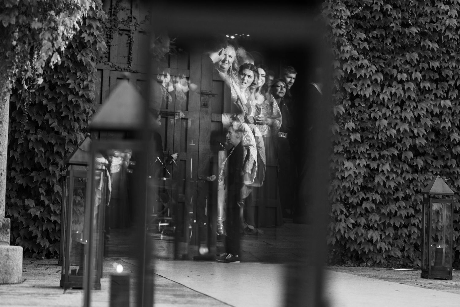 A black and white film strip showing multiple frames of someone walking down an ivy-covered corridor.