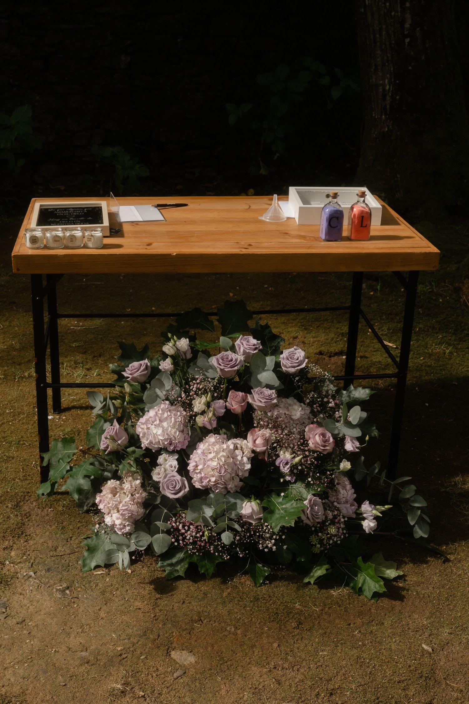 Rustic wooden table decorated with elegant pink and white floral arrangements at an outdoor wedding venue.
