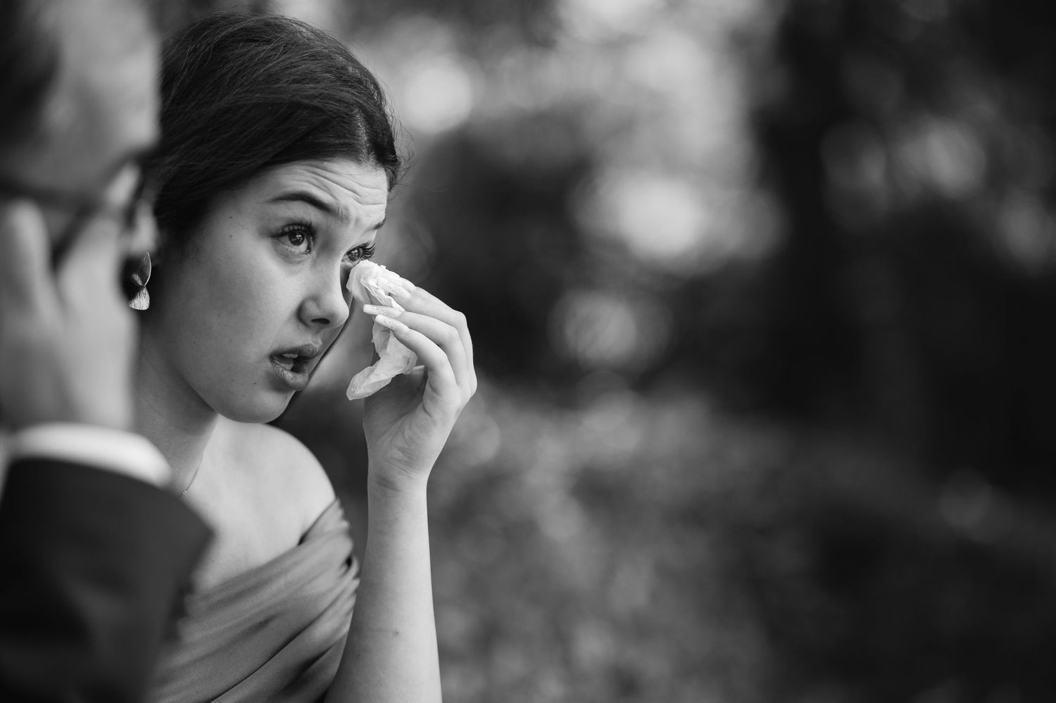 A black and white portrait photograph showing someone in contemplative pose with soft bokeh background.