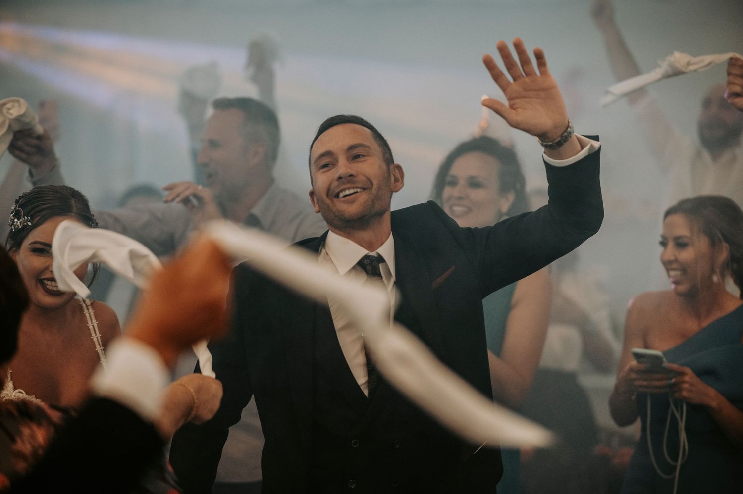 Crowd of people dancing and celebrating with raised hands at an energetic party or event.
