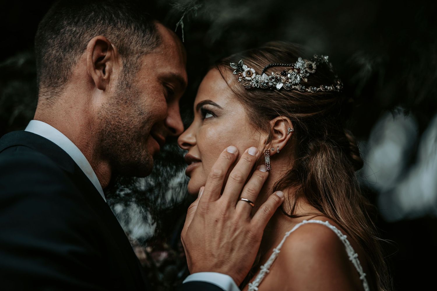 Romantic wedding couple sharing intimate moments in moody lighting and dramatic shadows.