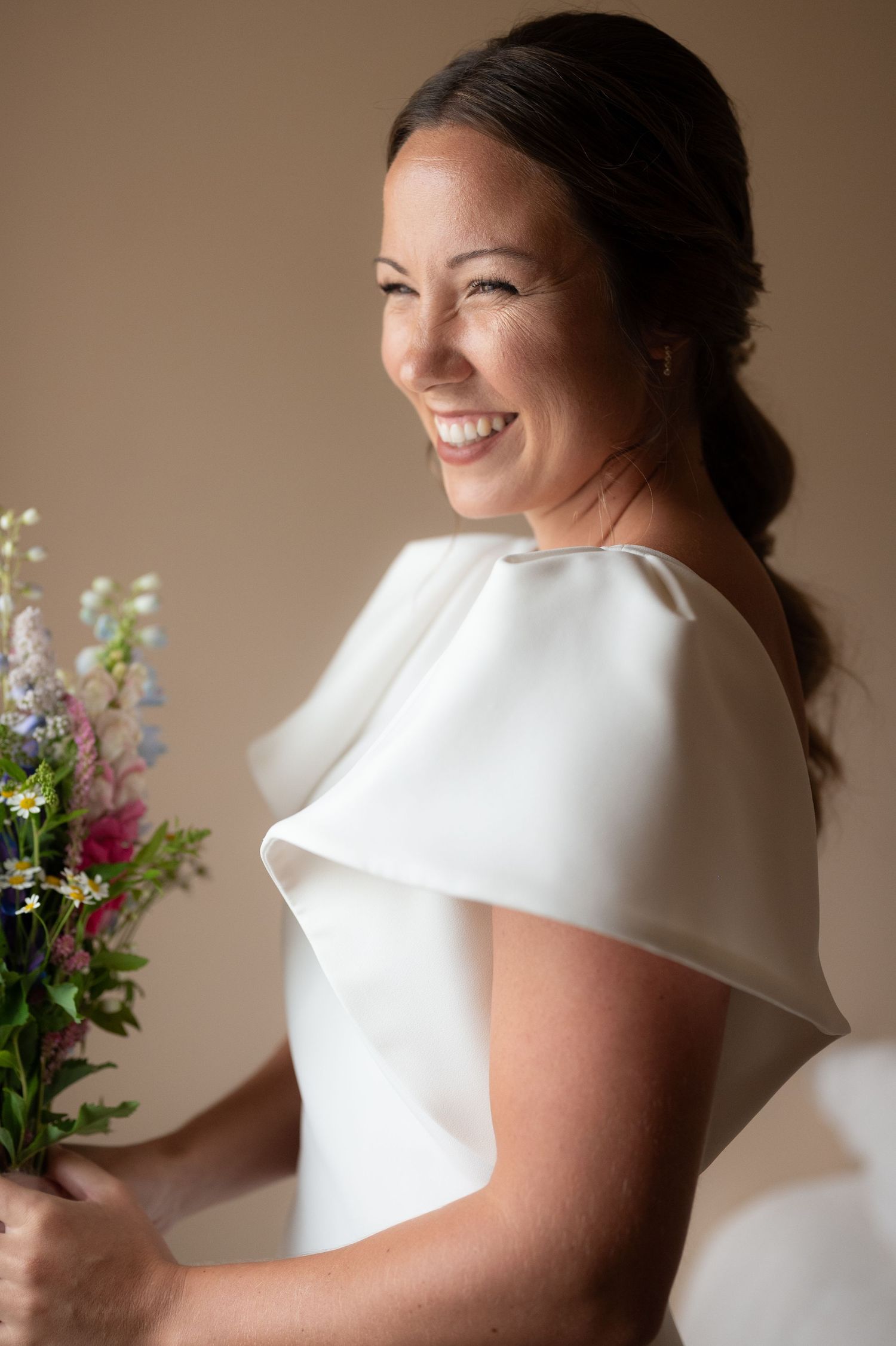 Candid moments of someone wearing an elegant white bridal gown with structured details and cap sleeves.