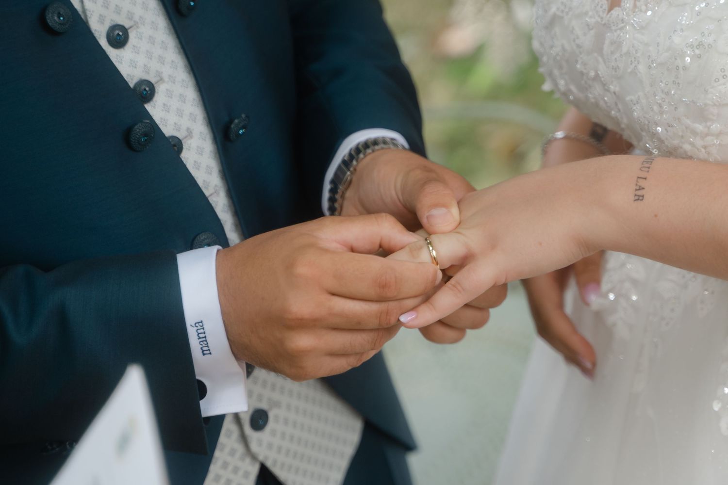 Close-up shot of hands during a wedding ceremony as a ring is being placed on the bride's finger.