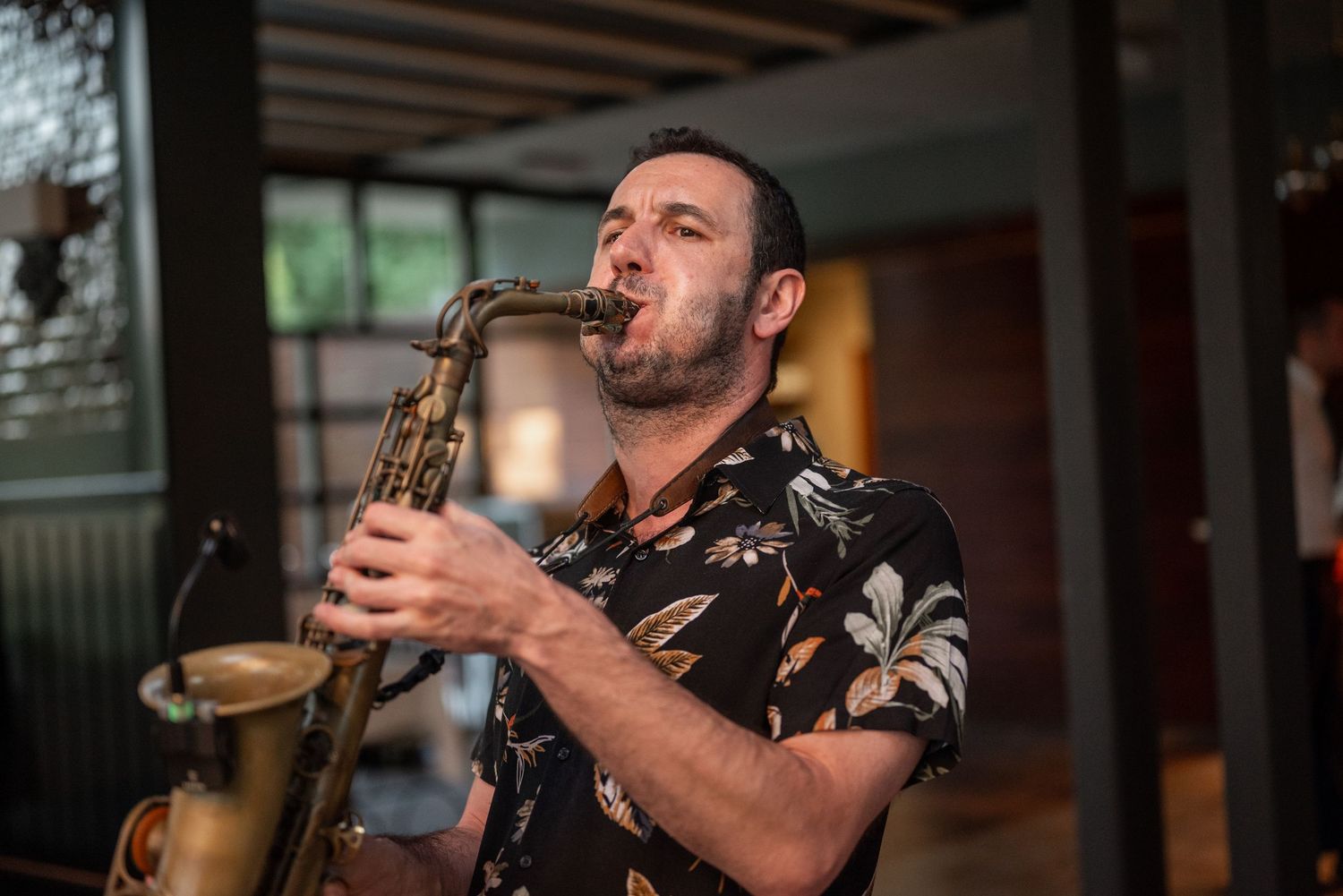 Live band performs with saxophone player on stage at an indoor event.