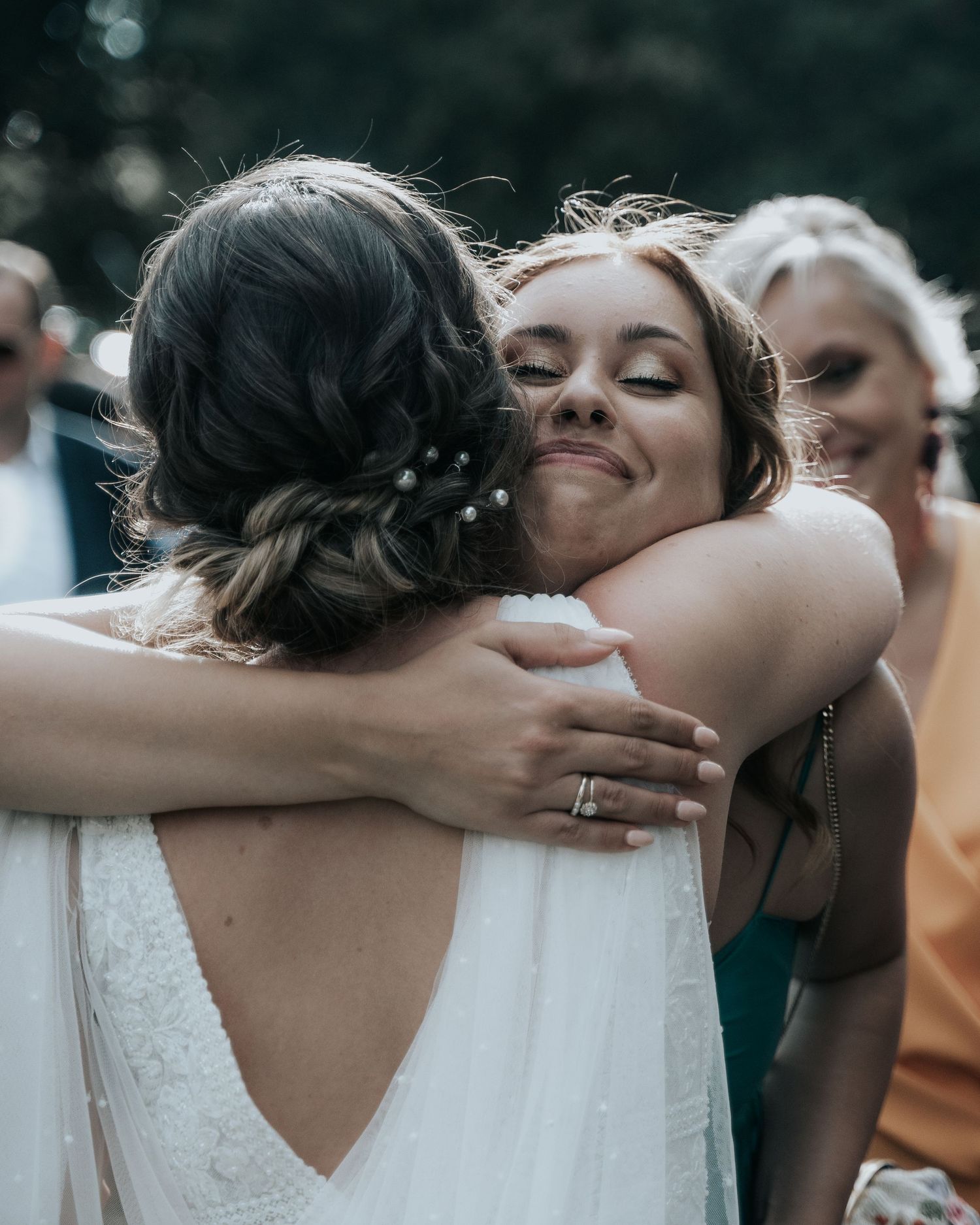 Wedding party members share joyful embraces and celebrations in an emotional group moment.