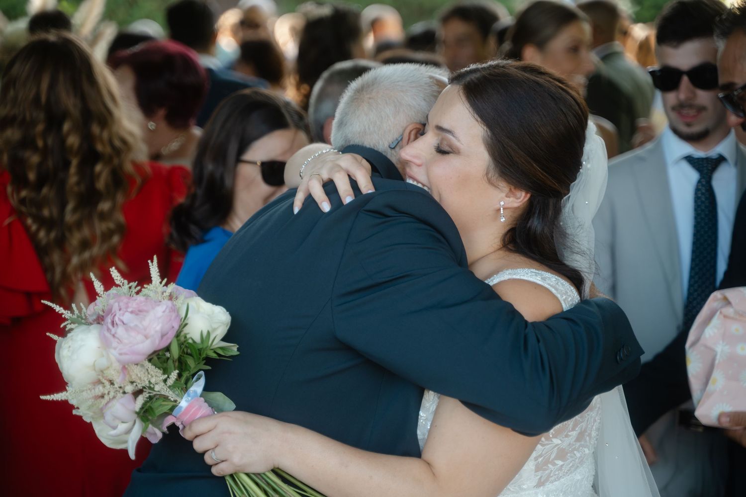 Emotional hugs and congratulations shared between wedding attendees outdoors.