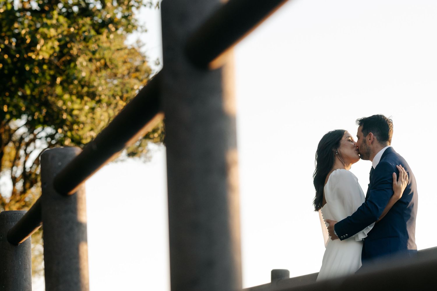 A romantic wedding couple embraces under tall pillars during a sunset photoshoot.
