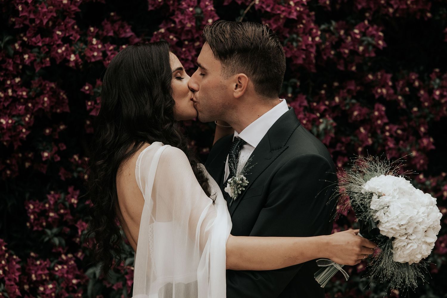 A couple shares romantic kisses under beautiful pink cherry blossoms in a series of wedding photos.
