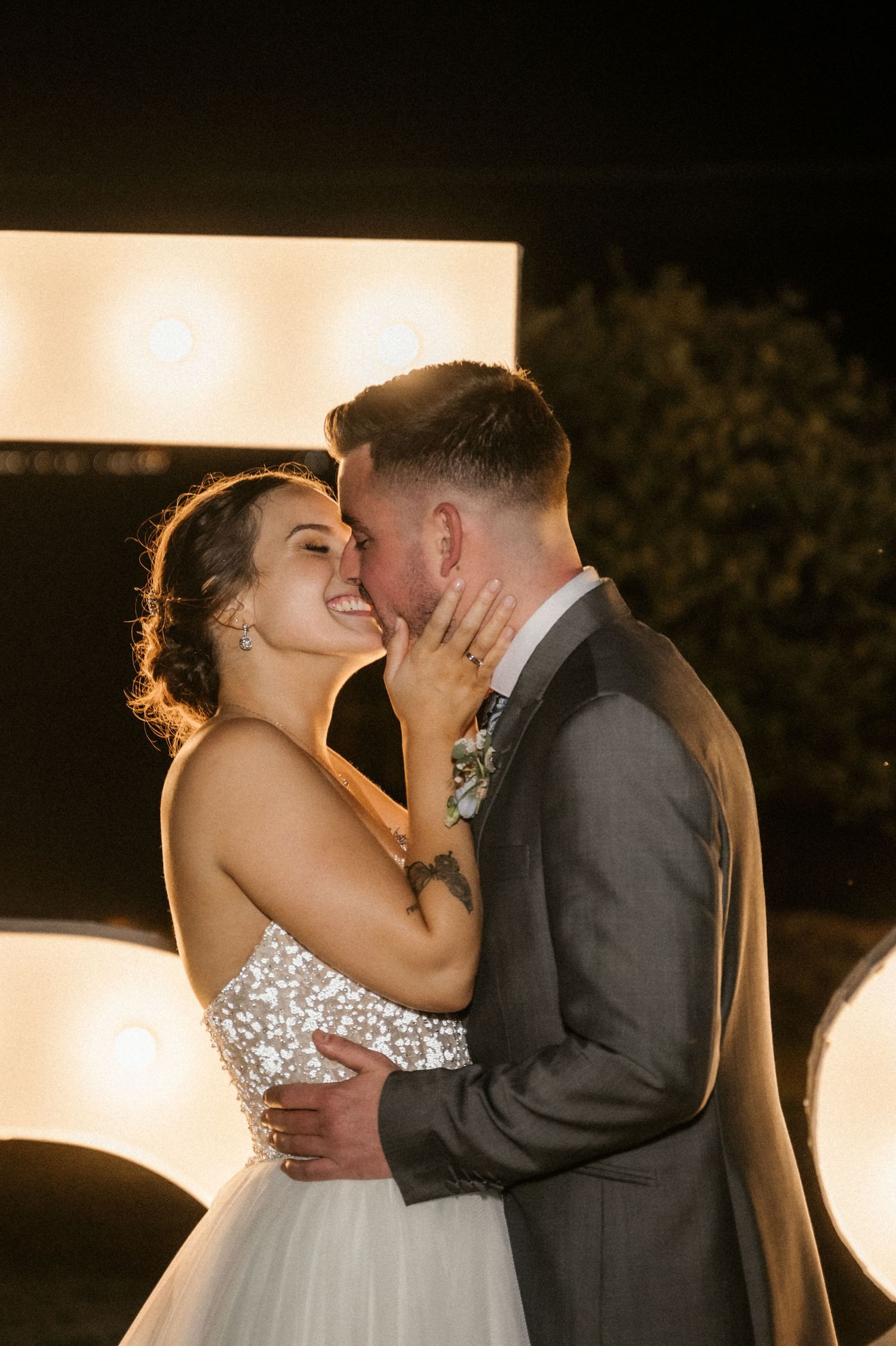 Newlyweds share an intimate dance moment under warm lighting during their evening wedding reception.