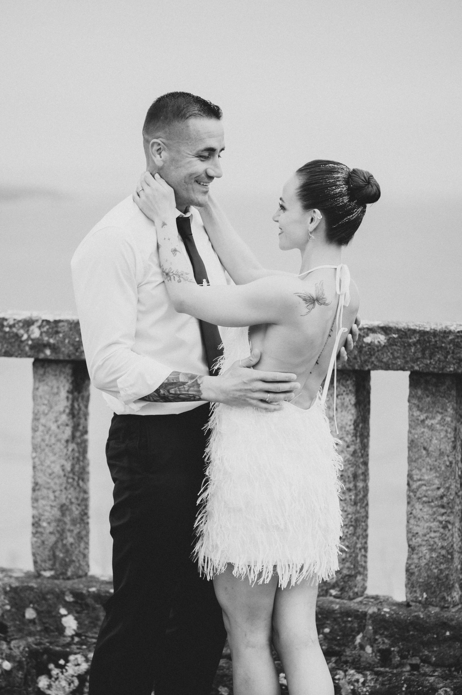 A series of black and white wedding photos showing a couple embracing near stone pillars.