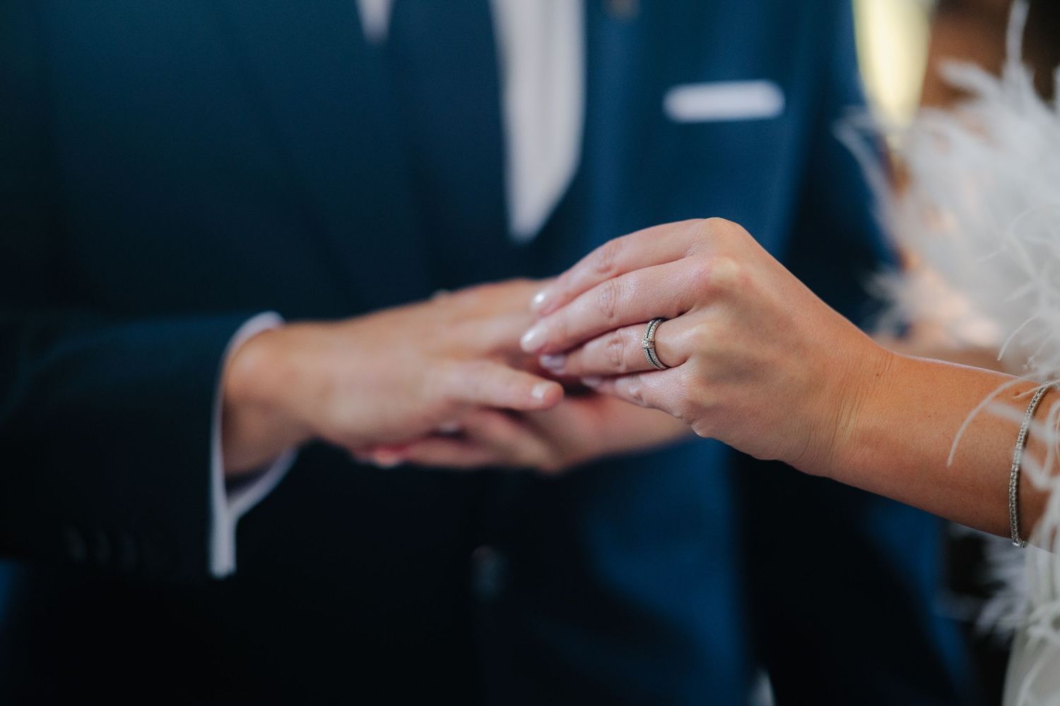 Close-up of hands exchanging wedding rings during ceremony.