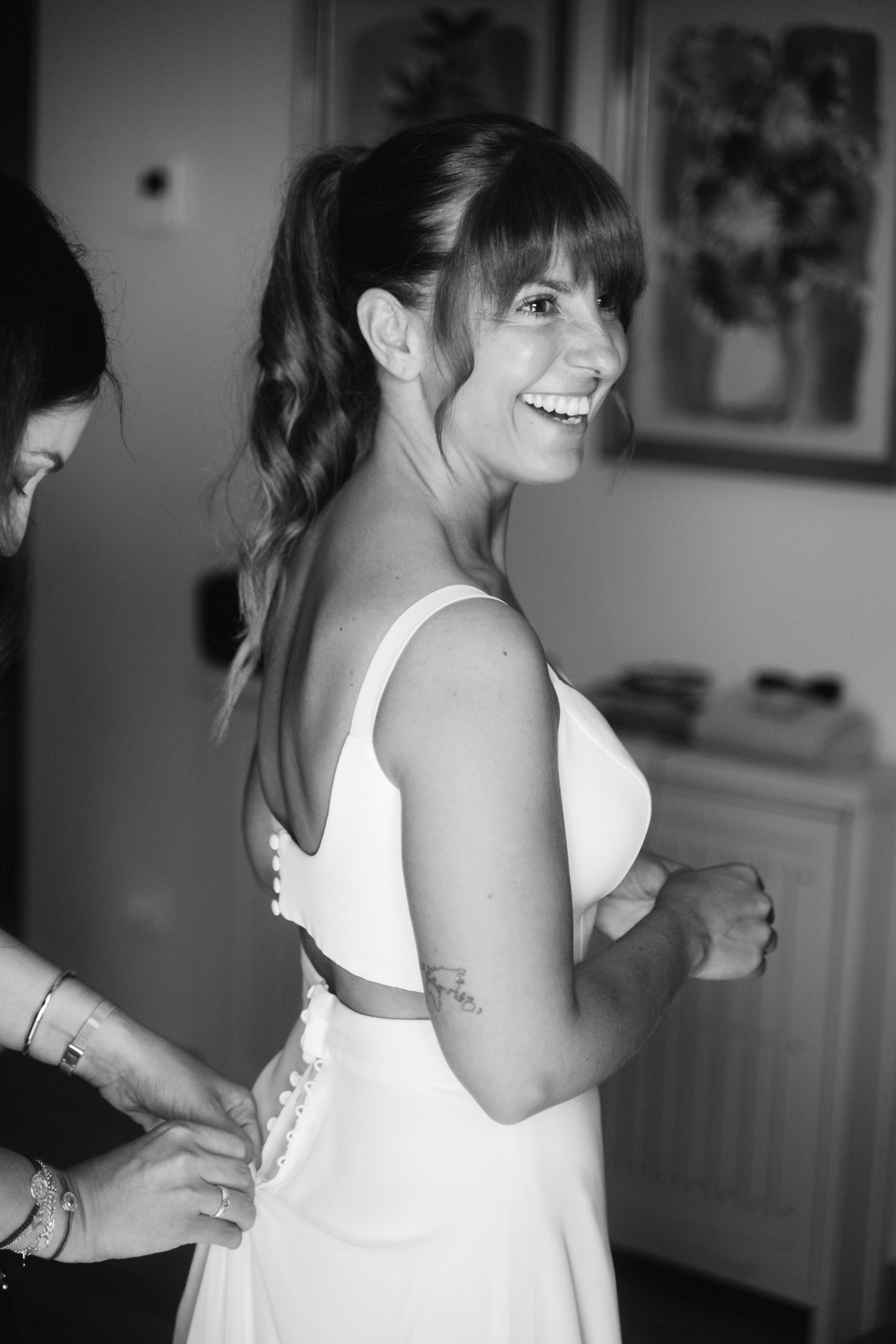 A sequence of black and white photos showing a person in a white dress being laced up from behind.